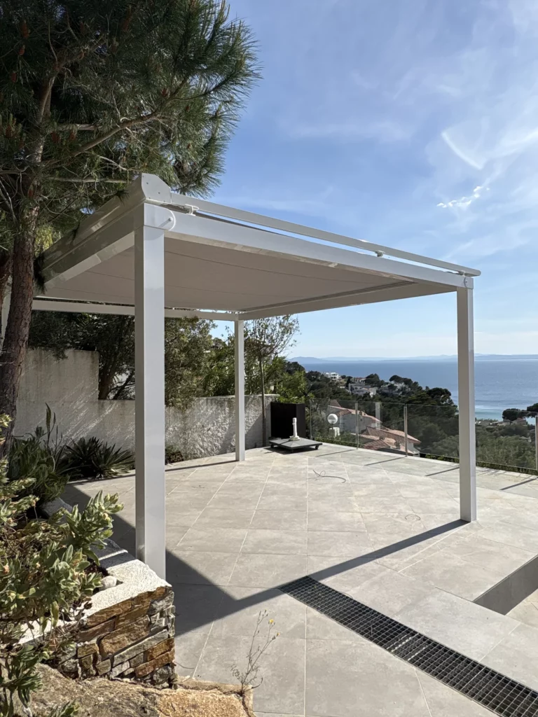 Un toldo veranda es un toldo que corre sobre guías en lugar de sostenerse con brazos. Eso le permite cubrir superficies grandes y quedar bien tensado, incluso en una terraza expuesta al viento como esta. Aquí va sobre una estructura propia con pilares, de manera que también funciona donde no hay pared donde sujetarlo. **Principales características:** - **Se abre y se cierra del todo:** decides si quieres sombra o si prefieres la terraza descubierta. - **La lona corre sobre guías:** queda tensa y estable, sin ondear con el viento como un toldo de brazos. - **Cofre motorizado:** al recogerse, la lona queda guardada y protegida del sol y de la lluvia. - **Con estructura propia:** los pilares permiten cubrir la terraza sin depender de la fachada. Toldo veranda con guías laterales y cofre motorizado en Roses